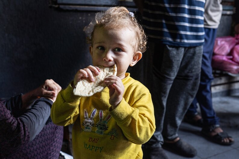 A young child eating freshly baked bread in Gaza.