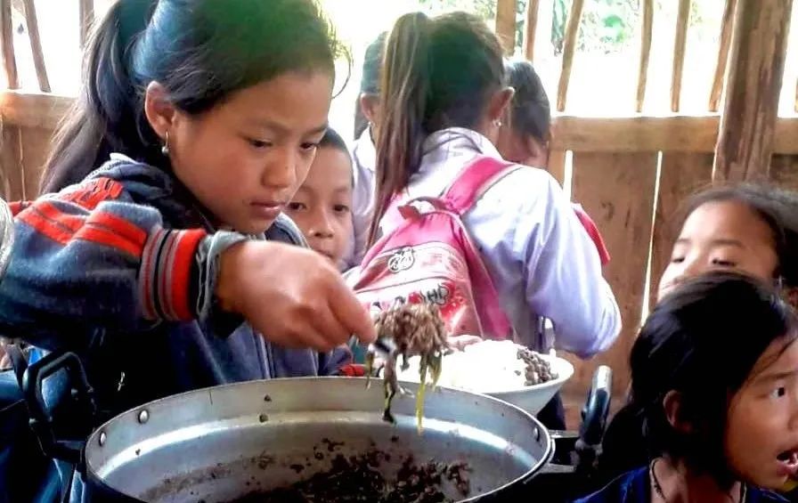 项目受益儿童正在帮忙分发营养餐。照片© WFPLaos / PhonnickHuckchaleun