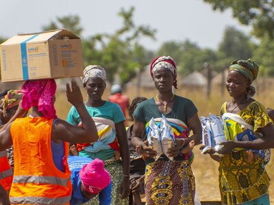 Women with a child on their back, have just received packets of Corn Soya Blend (CSB+).