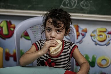 A young girl eating bread distributed by WFP at UNRWA school that is a designated shelter in times of emergency.
