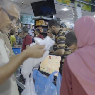 Man putting food into a bag for a woman inside shop