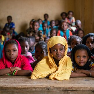 Nafissatou, 11-years-old, poses for a photograph with her friends in the classroom of the Alpha Amadou Diallo Guetema school.