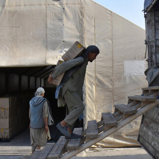 WFP staff carrying boxes of WFP fortified food assistance to be distributed in Afghanistan.