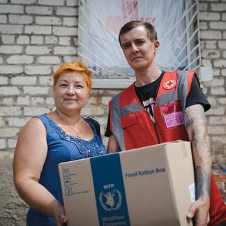 Woman receiving food rations from a WFP staff in frontline areas in Ukraine